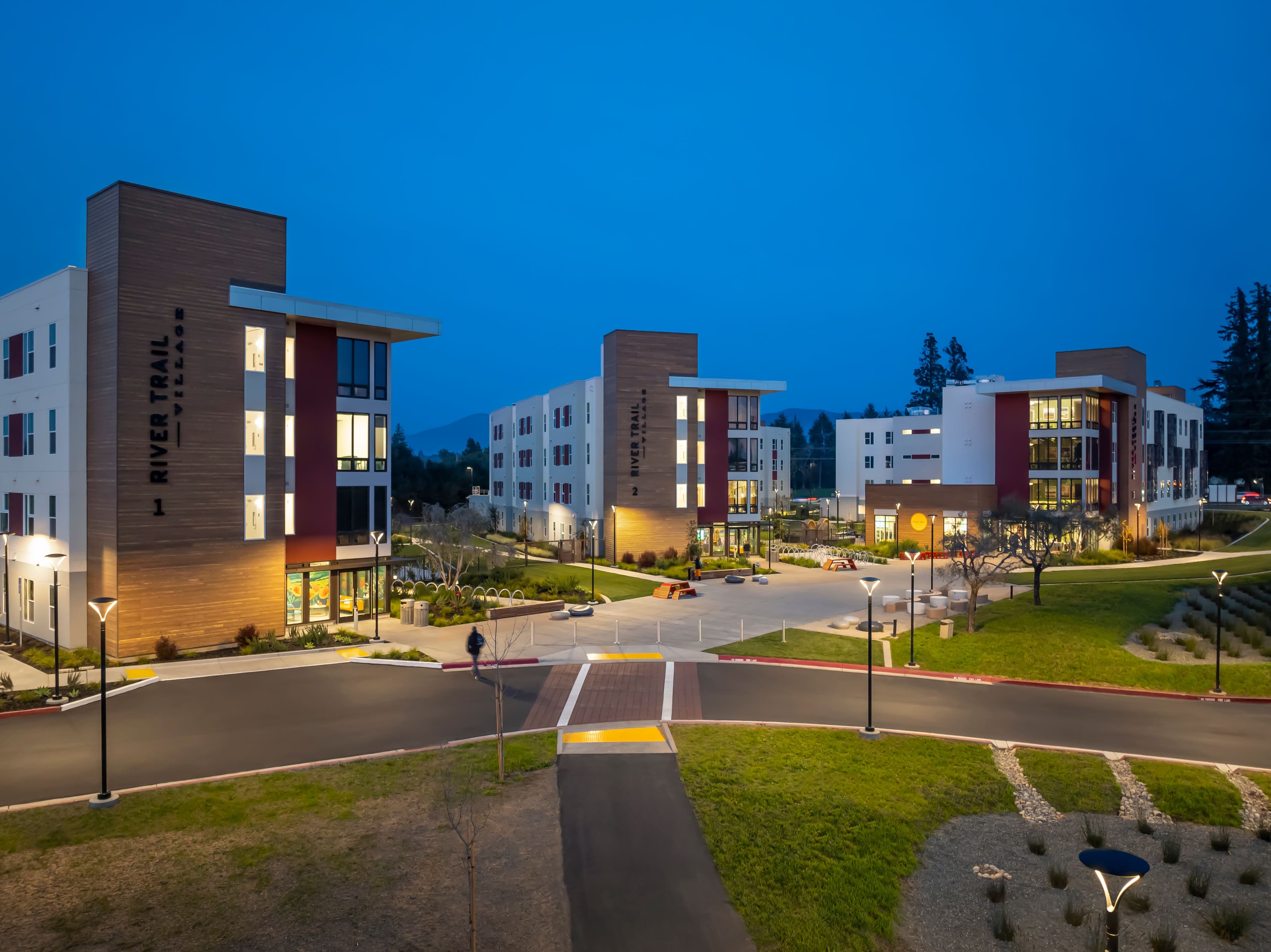 River Trail Village at dusk, three residential buildings around a lit courtyard and walkways at Napa Valley College