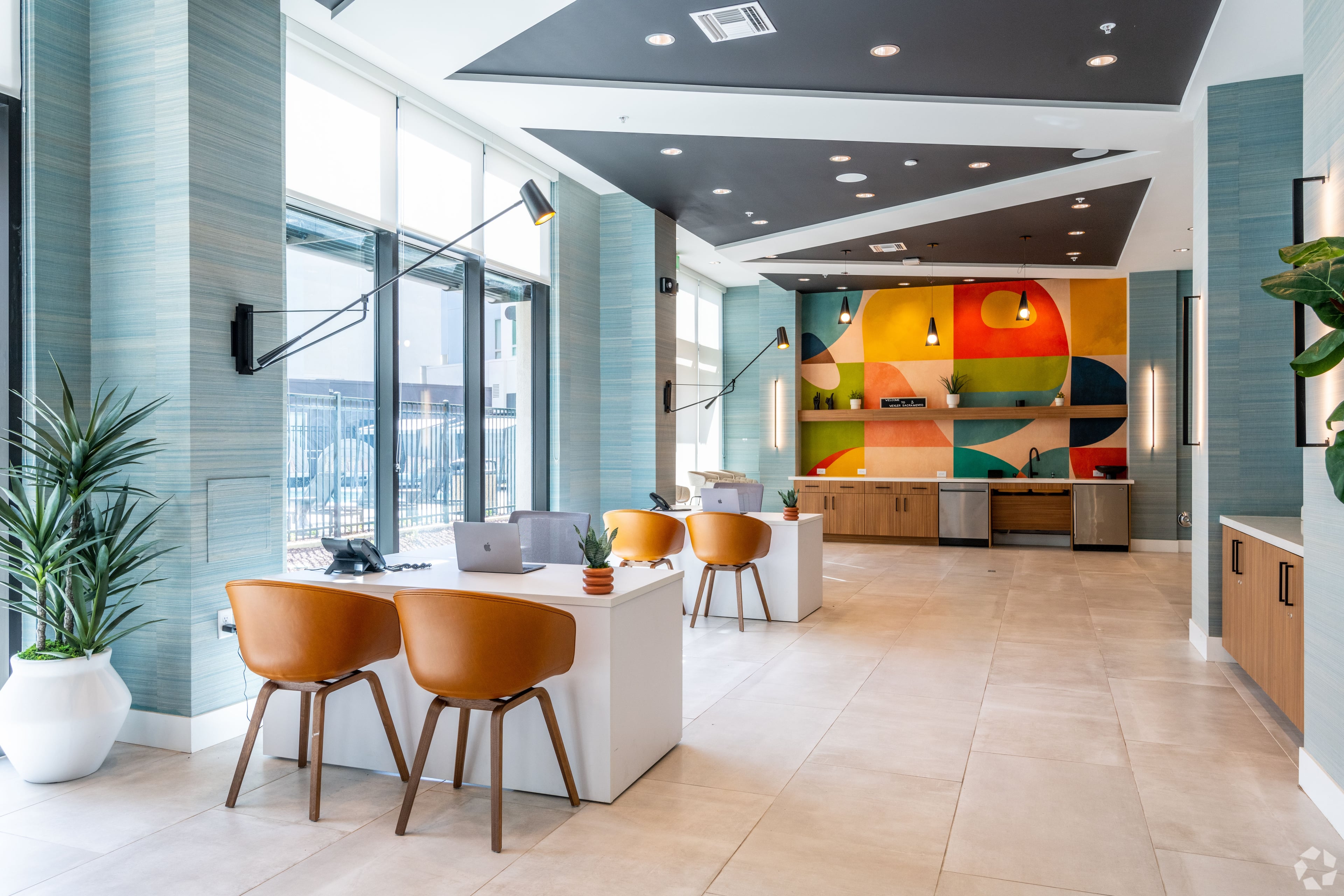 Leasing area with orange chairs, white desks, and a colorful mural on the back wall
