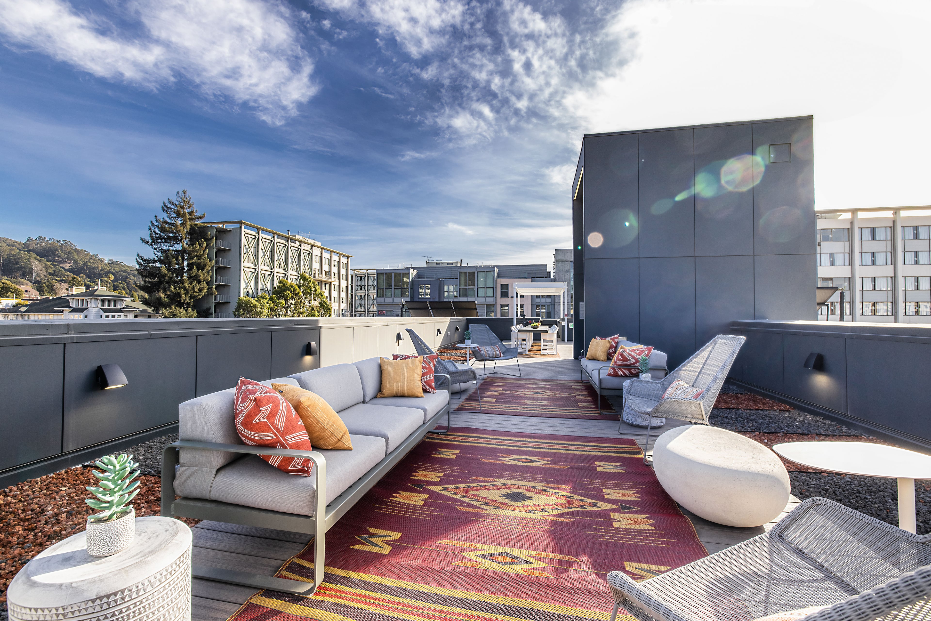 Rooftop deck with a sectional, patterned rug, and Berkeley buildings behind