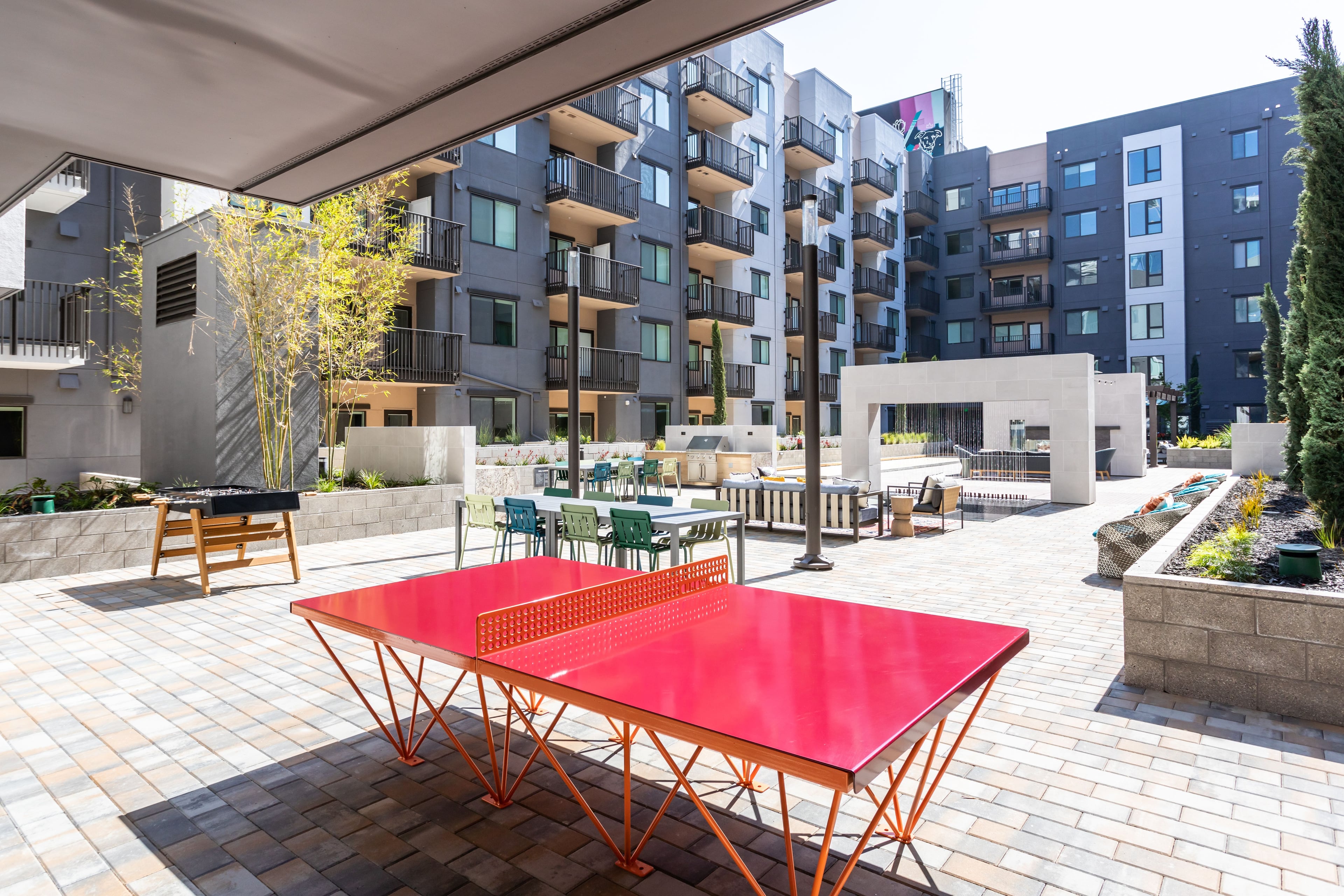 Courtyard with a red ping-pong table, planted beds, and apartment wings on three sides