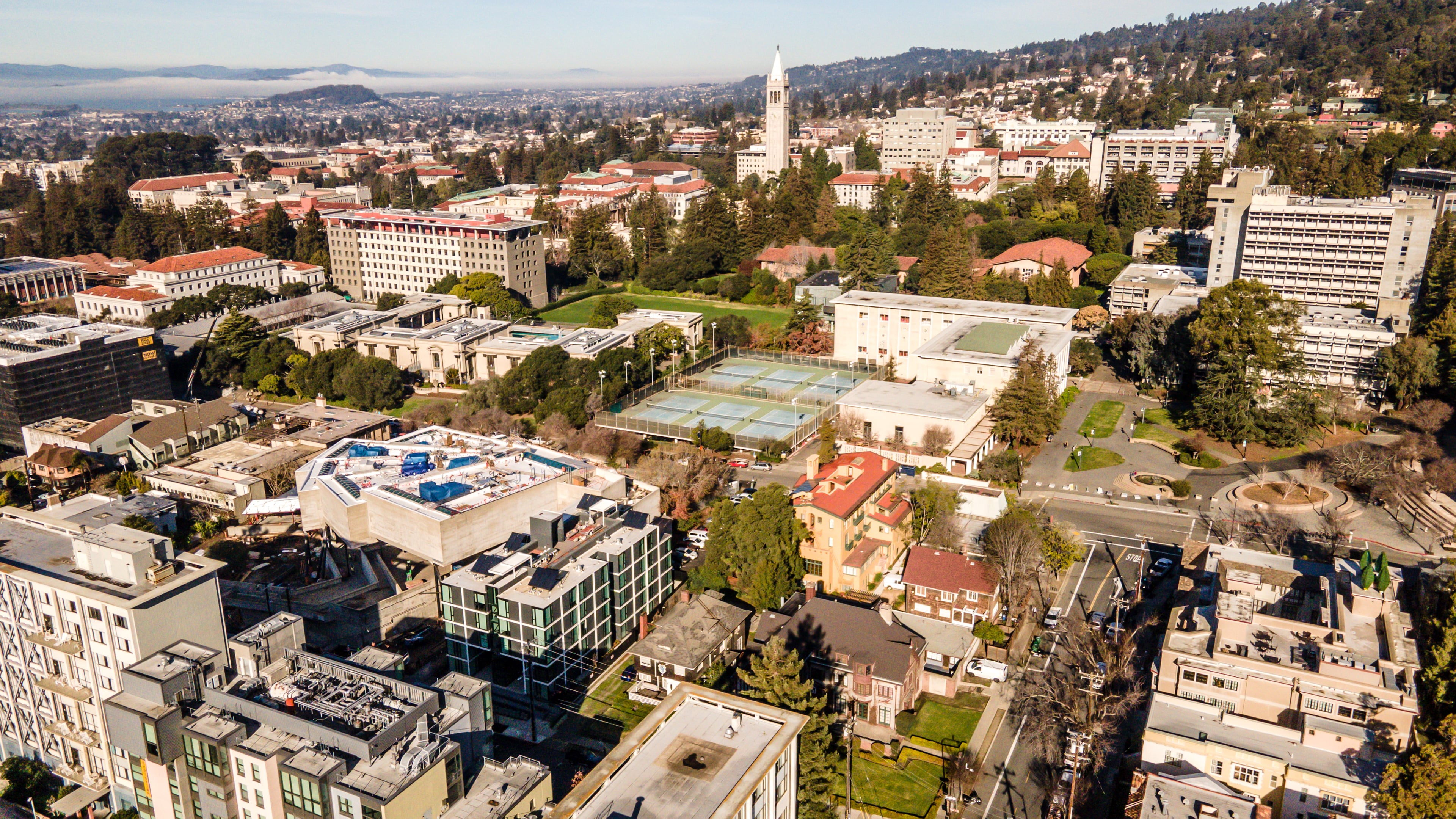 Aerial view of The Durant among neighboring buildings, with the UC Berkeley campus, the Campanile and the Berkeley hills behind