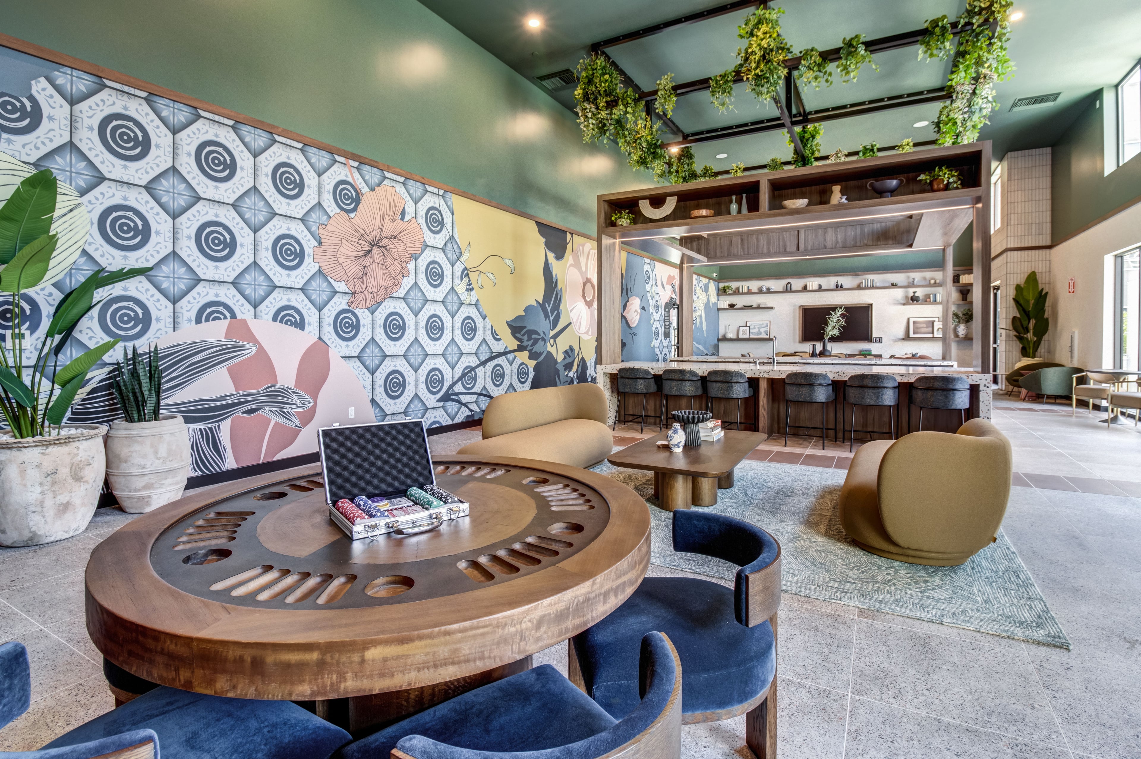 Game lounge with a round poker table, a patterned tile wall, and hanging plants