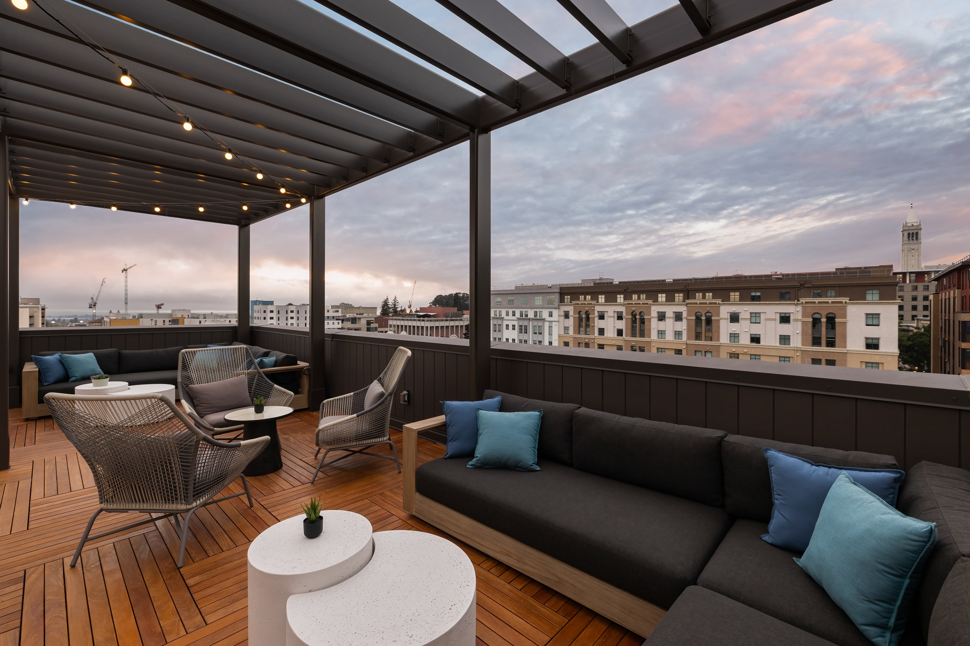 Rooftop lounge under a pergola at sunset, Berkeley rooftops and the Campanile beyond