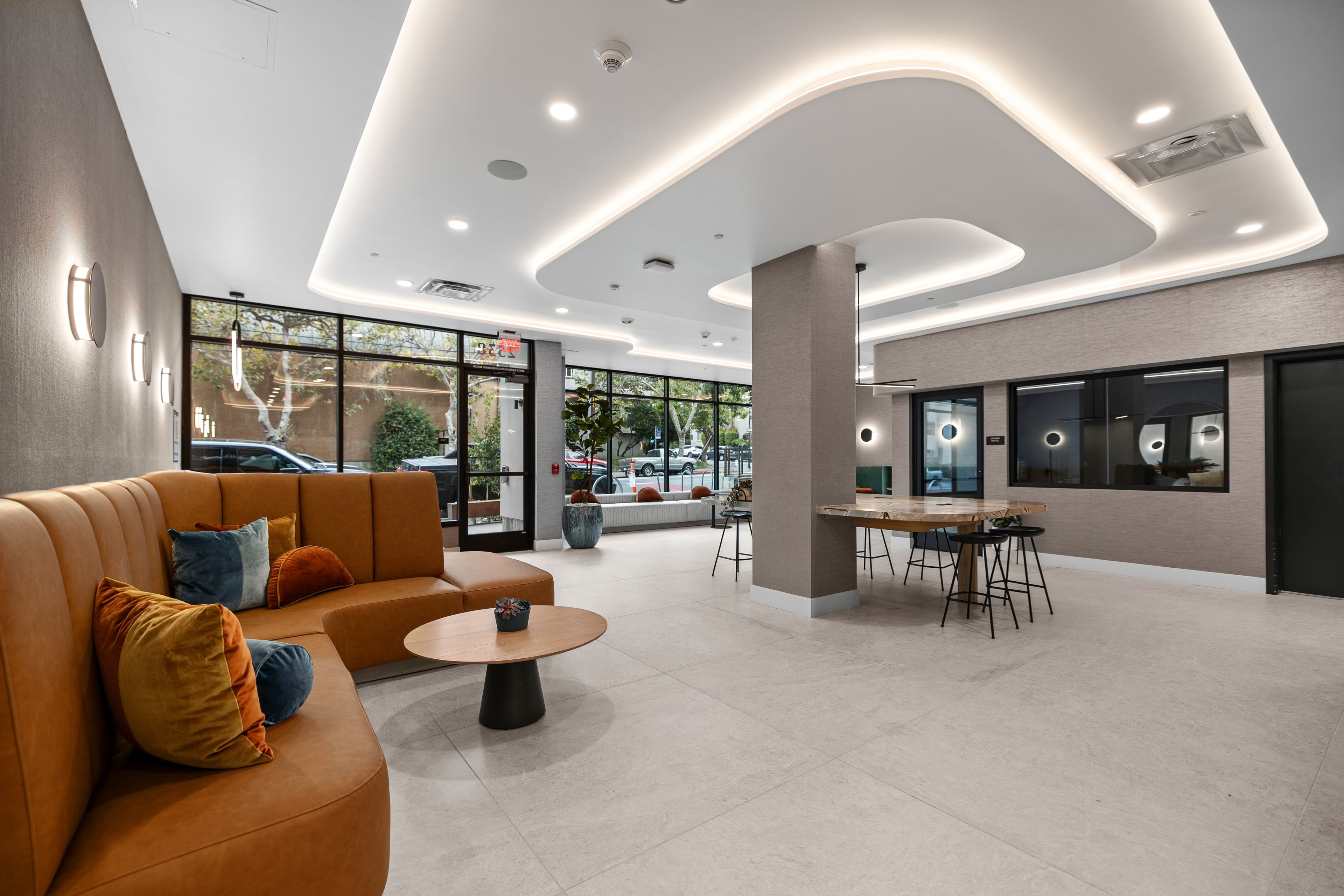 Lobby with a curved orange sofa, sculpted ceiling coves, and a communal table