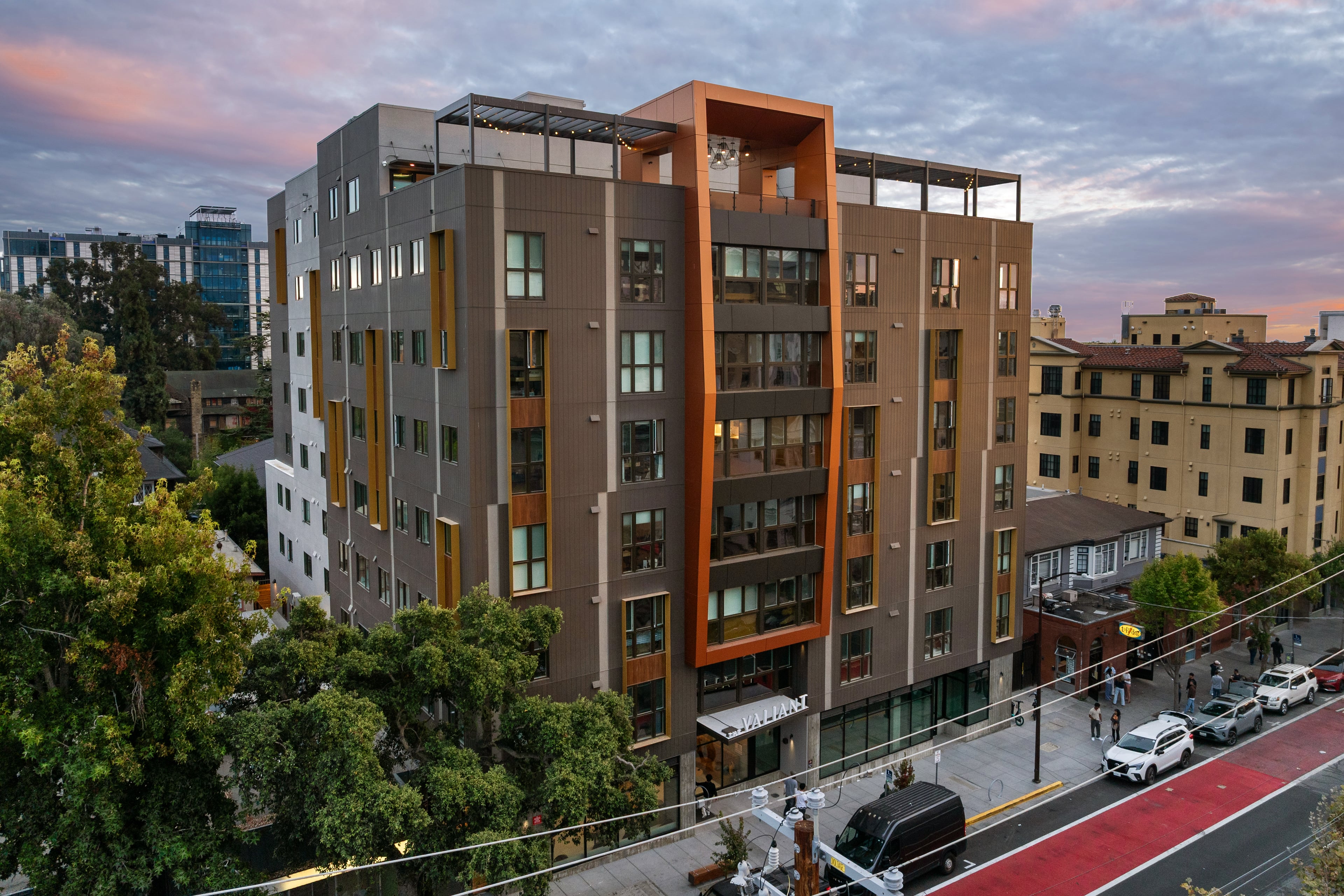 The Valiant at dusk, an eight-story building with bronze panels and orange accents on a Berkeley street