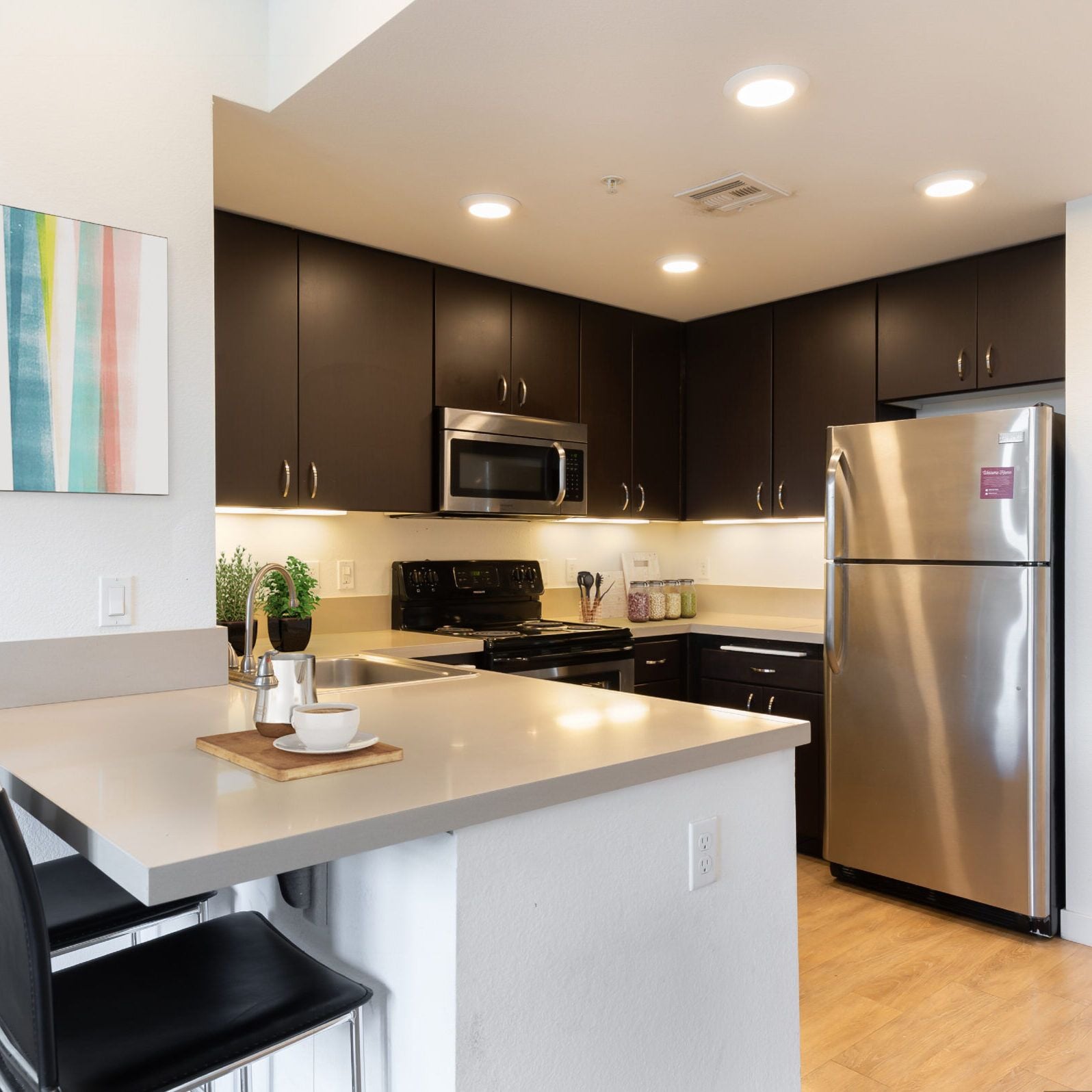 Kitchen with dark cabinets, a white counter, and stainless appliances