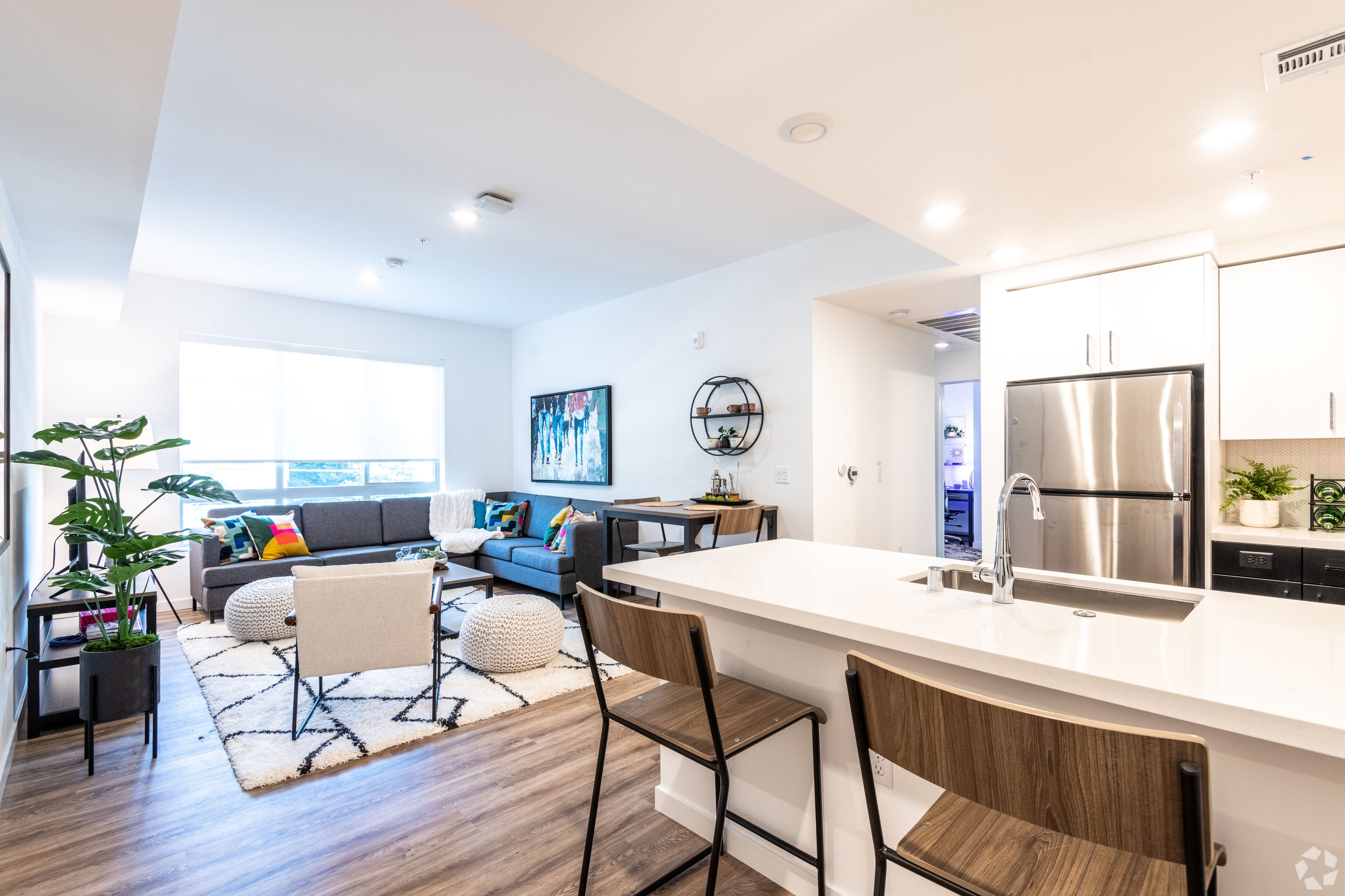 Furnished apartment with a white kitchen island, blue sofa, and TV