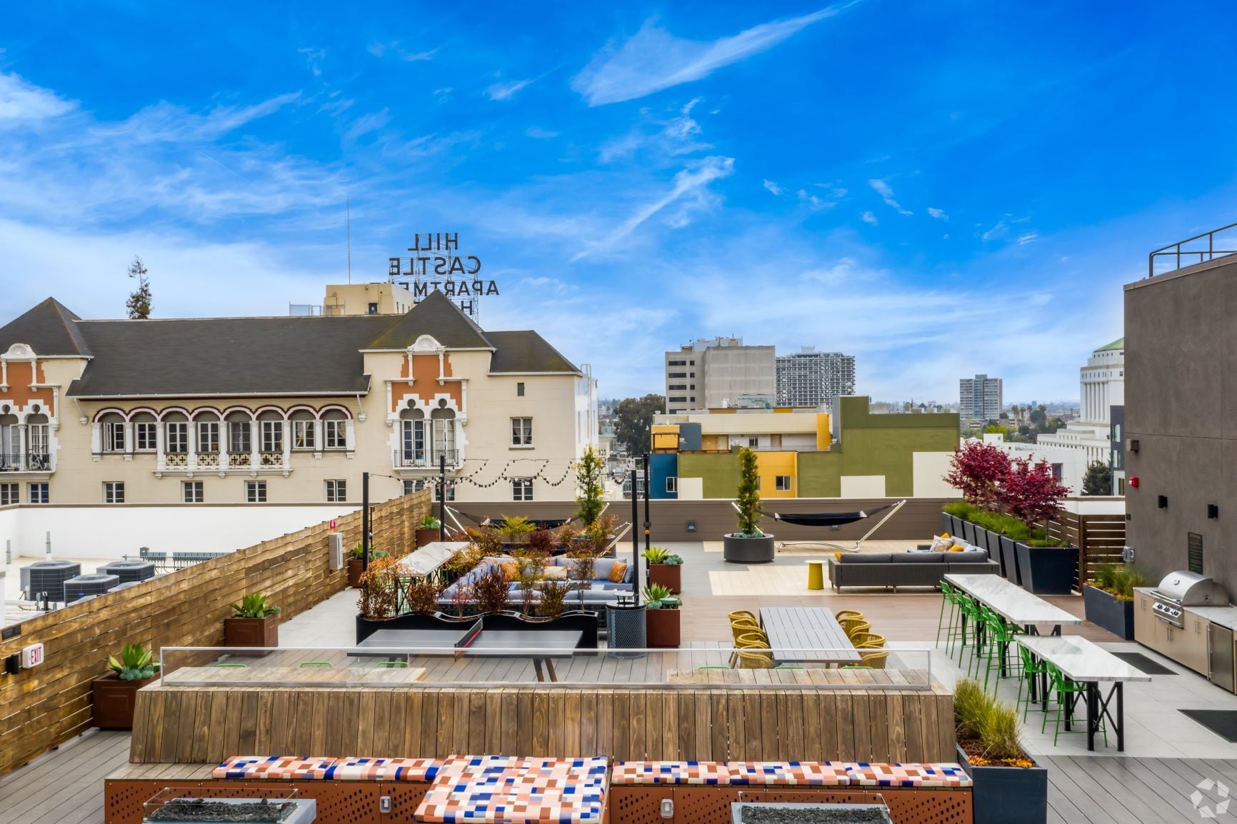 Rooftop deck with planters and a wood screen, downtown Oakland buildings and an older apartment block beyond