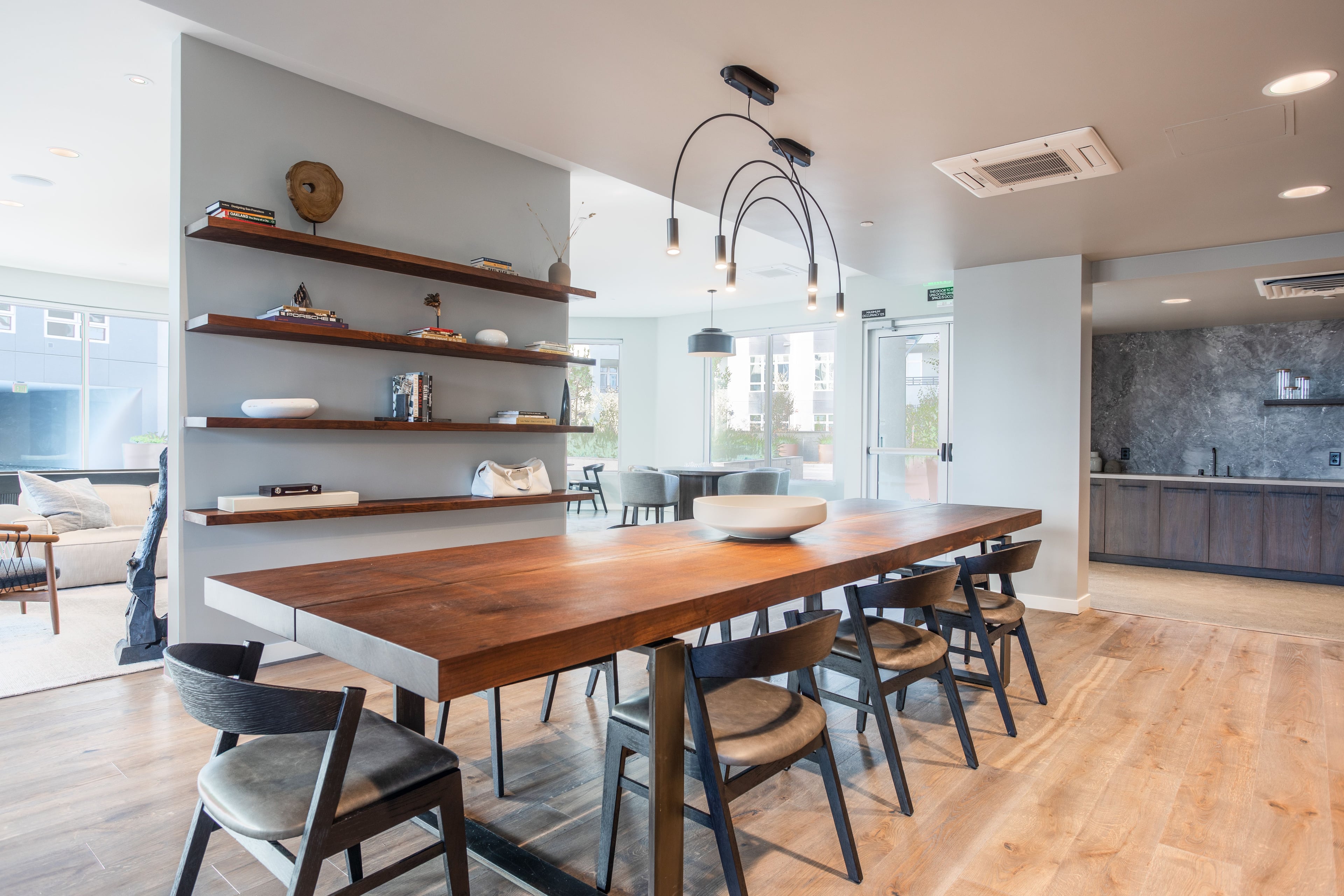 Resident lounge with a long live-edge wood table, pendant lights, and open shelving