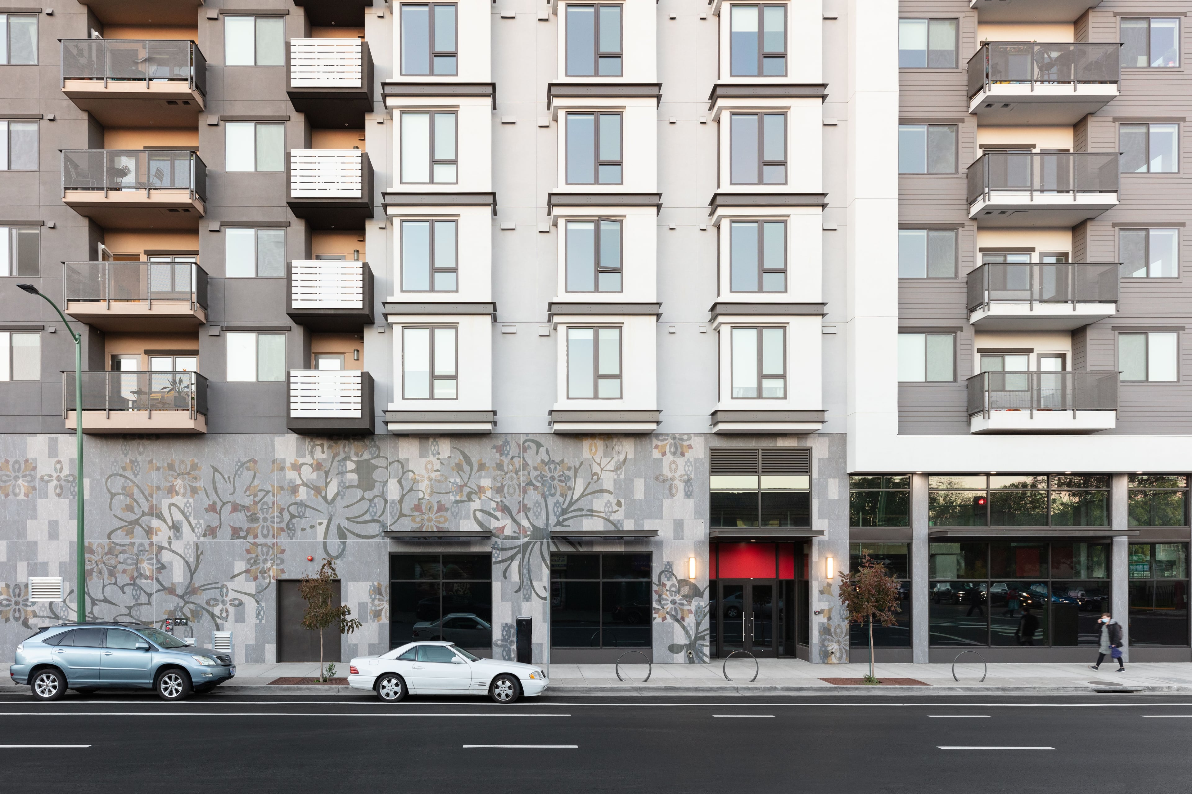 Street-level facade with patterned art panels wrapping the base of the building and balconies above