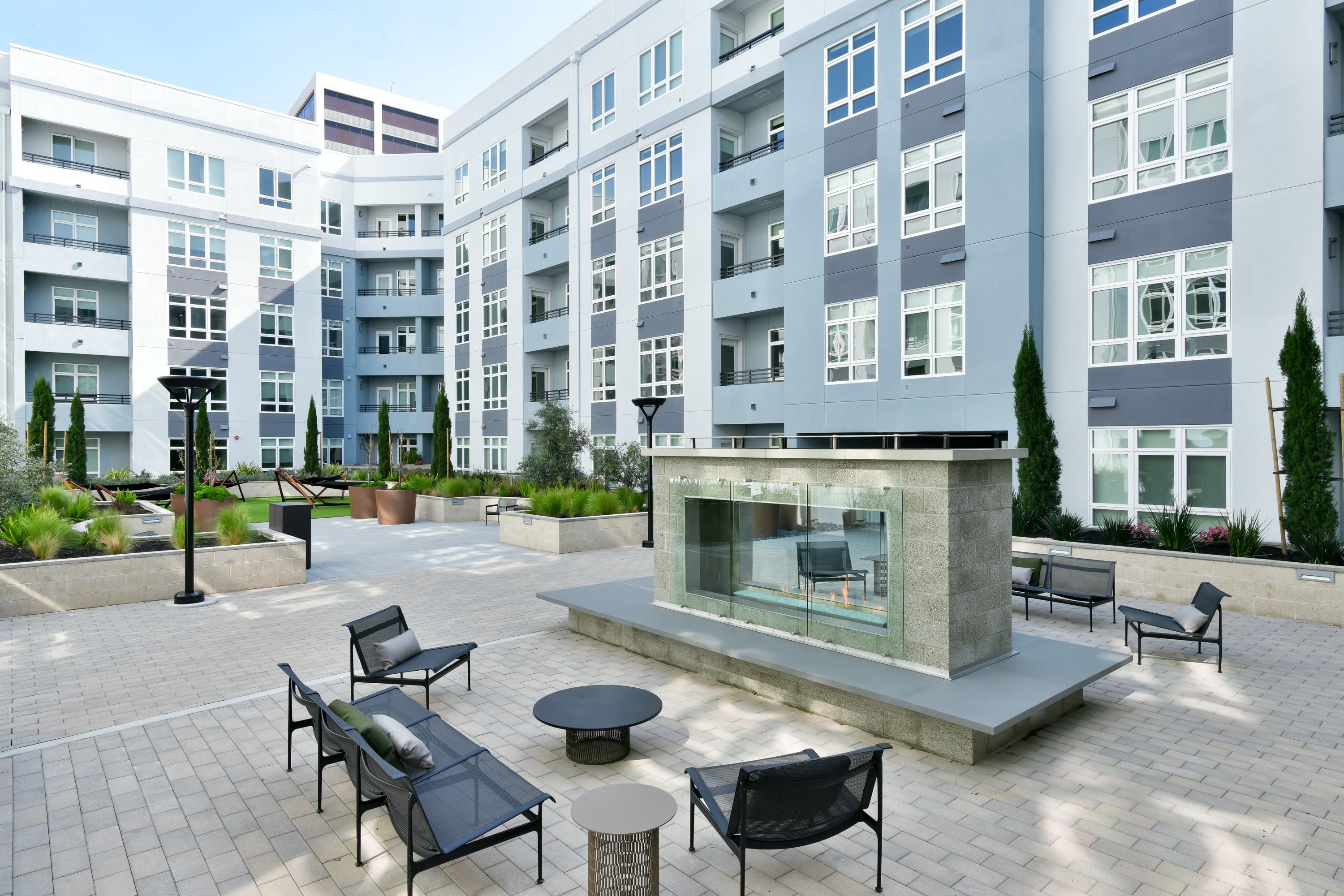 Courtyard with an outdoor fireplace, lounge chairs, and apartment wings on three sides