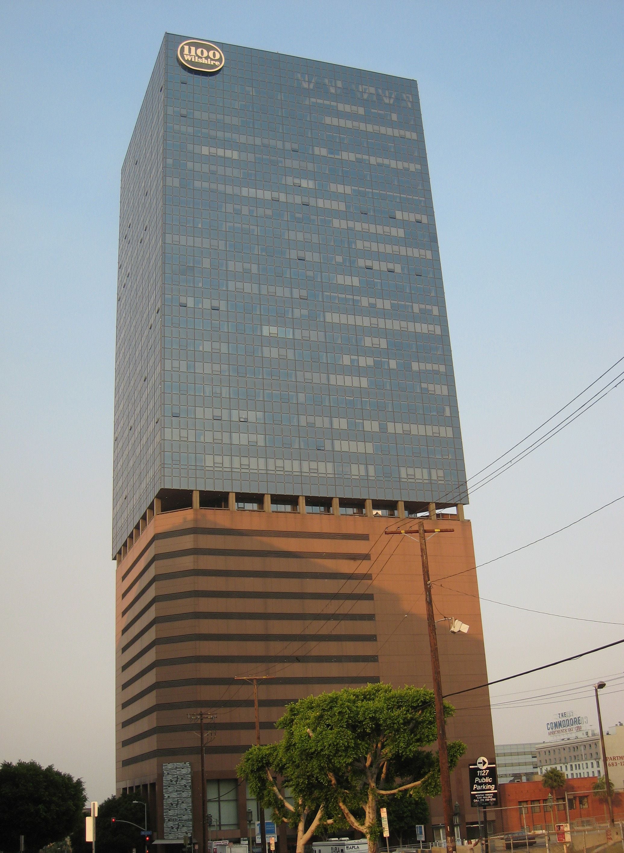 1100 Wilshire, a 37-story glass tower on a stepped garage base against a hazy sky