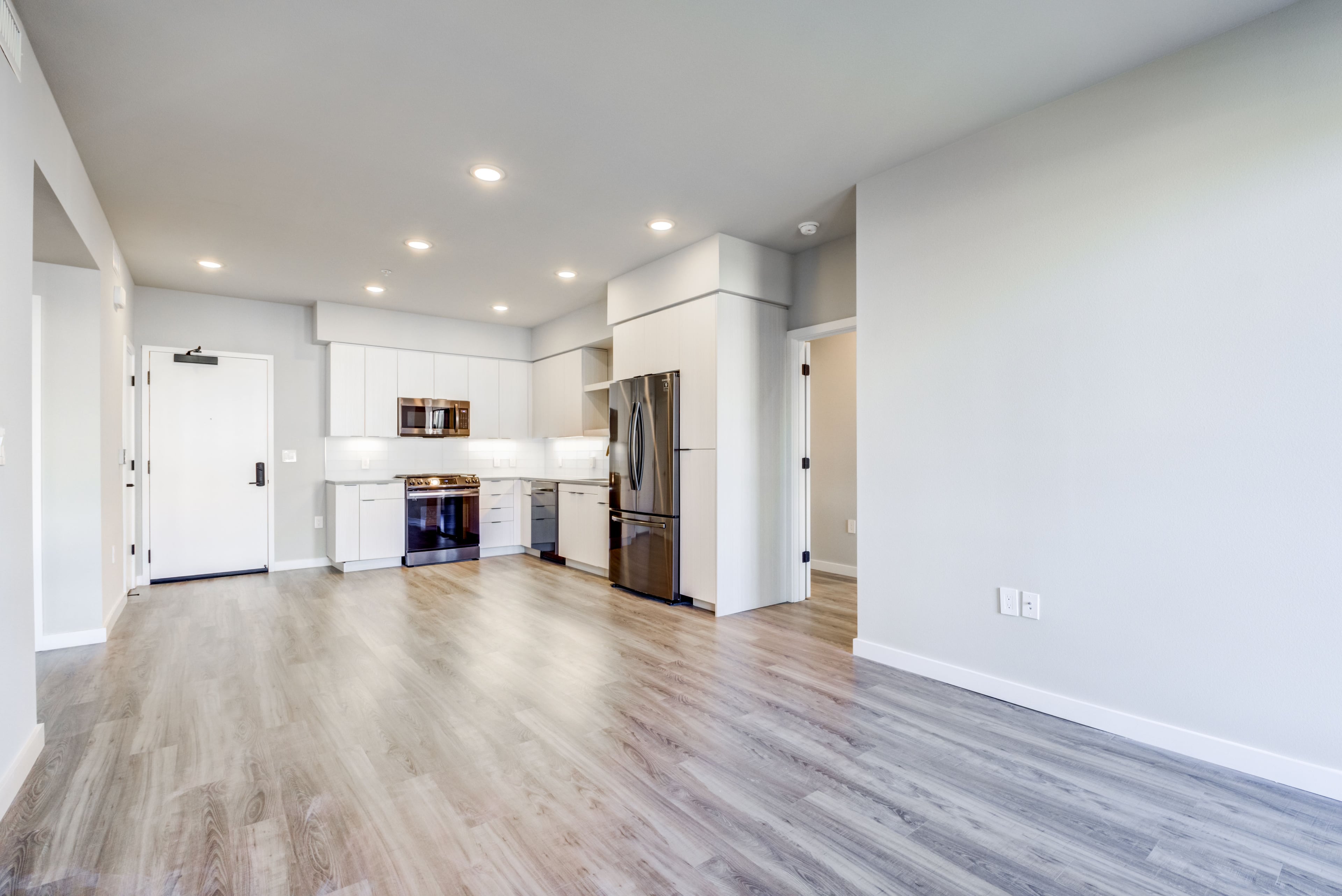 Empty open-plan apartment with a white kitchen along the far wall