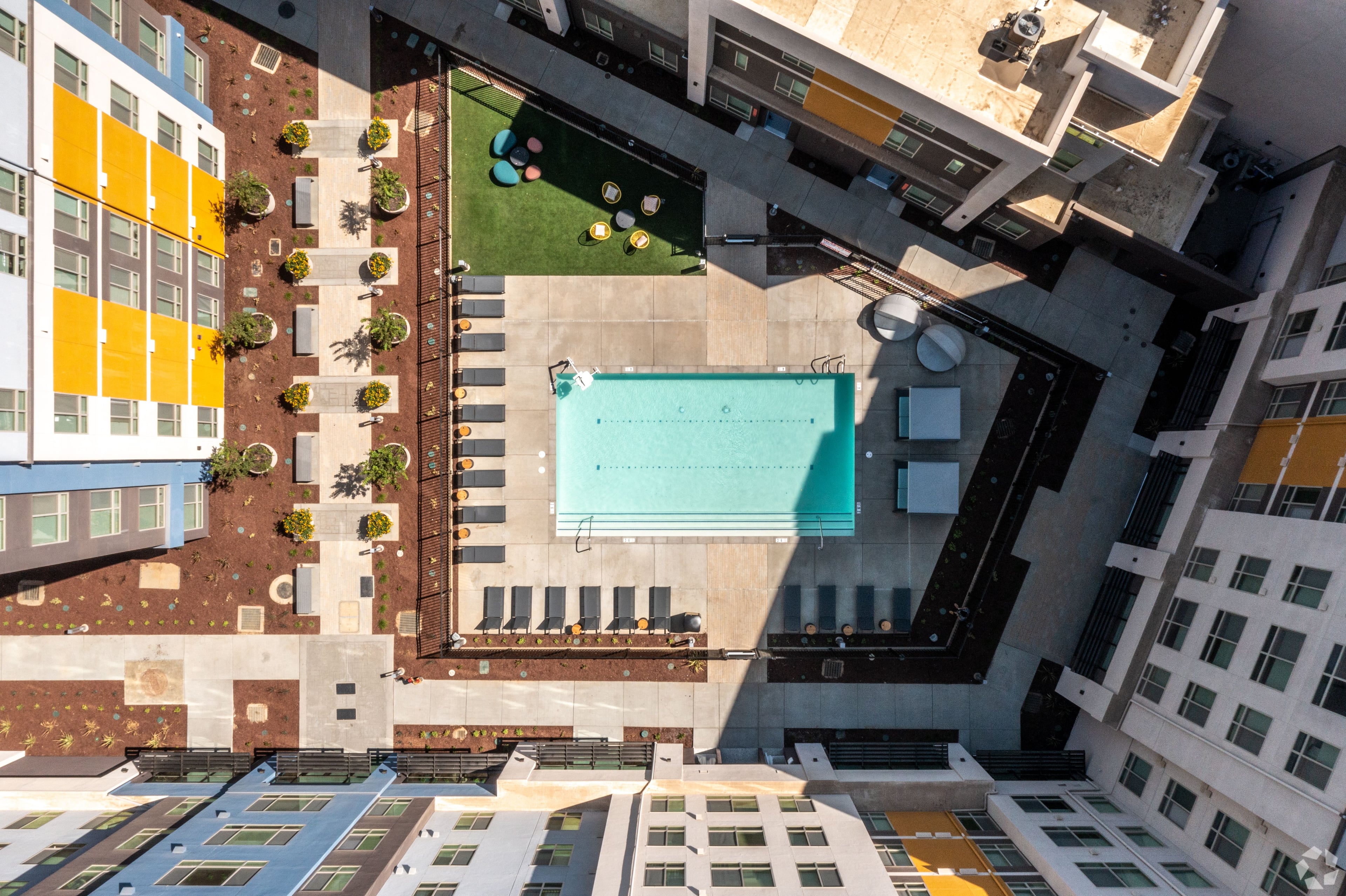 Aerial view straight down onto the pool courtyard surrounded by the building’s four wings
