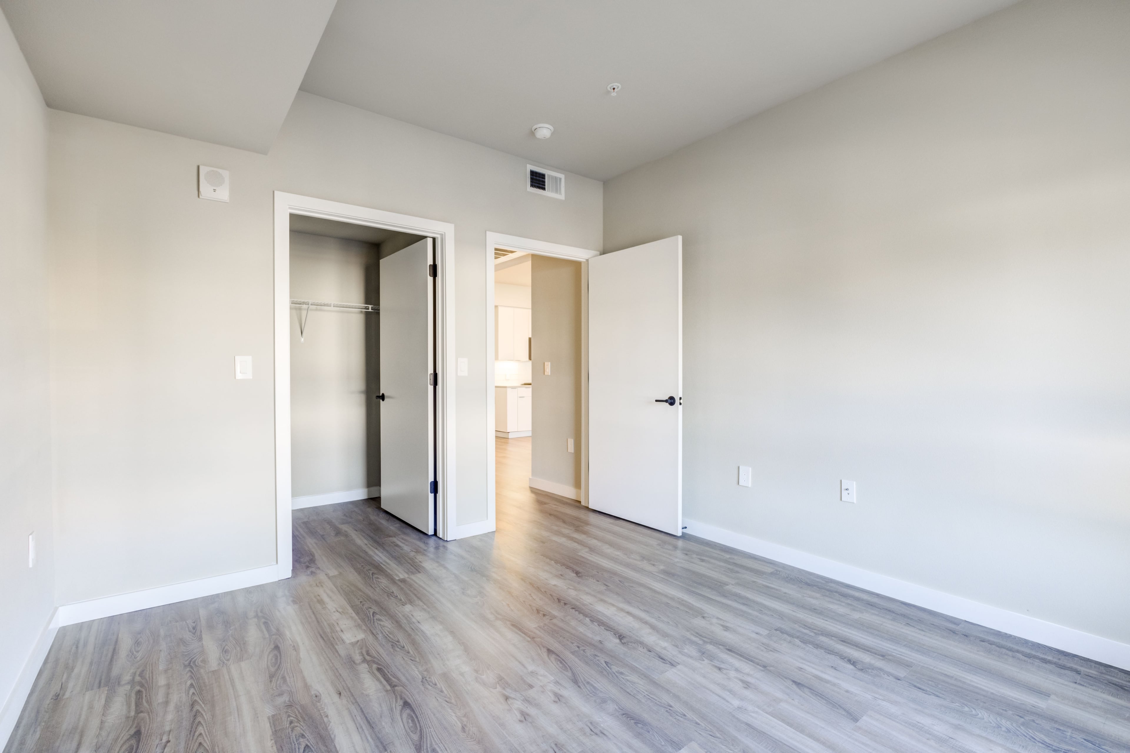 Empty bedroom with light wood floors, a closet, and an open door